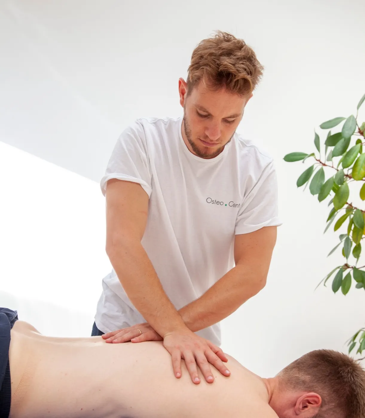 Osteopaat Bram Hulsbos onderzoekt met zijn handen de rug van een cliënt